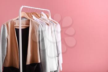 Rack with stylish clothes on color background�