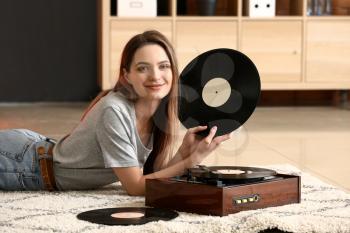 Young woman with old record player and vinyl discs at home�