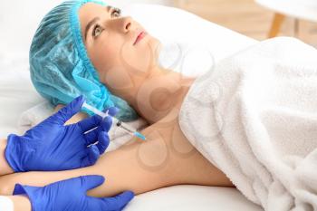 Woman receiving botox injection in armpit as treatment of hyperhidrosis in beauty salon�