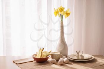 Tasty Easter cookies with milk and eggs on table in room�