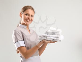 Portrait of beautiful female housekeeper with clean towels on white background�