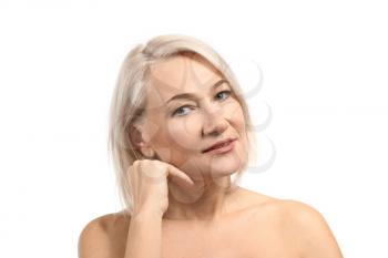 Mature woman giving herself face massage on white background�