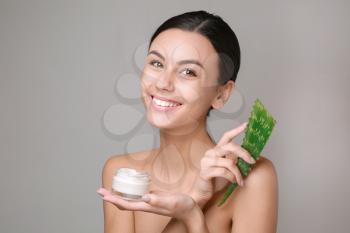 Portrait of beautiful woman with cream and aloe vera on grey background�