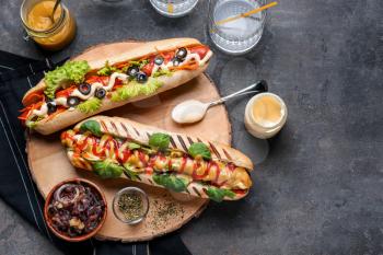 Tasty hot dogs with sauces on grey table�