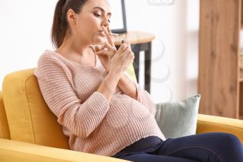 Pregnant woman smoking at home�