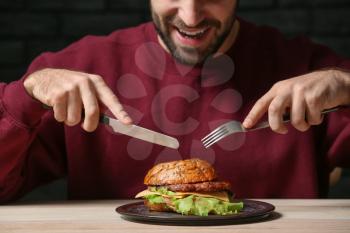 Man eating tasty burger at table�
