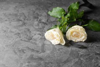 Rose flowers and black mourning ribbon on grunge table�