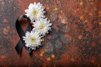 Black mourning ribbon and flowers on grunge background�