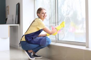 Beautiful woman cleaning window at home�