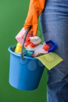 Woman with set of cleaning supplies on color background�