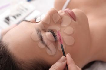 Young woman undergoing eyelash extension procedure in beauty salon�