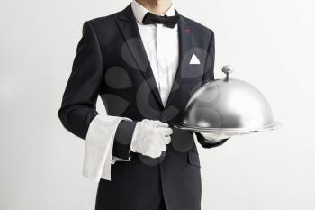 Waiter with tray and cloche on light background�