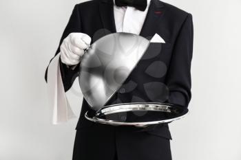 Waiter with tray and cloche on light background�