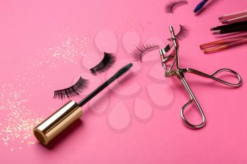 Mascara with false eyelashes and tools on color background�