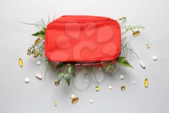 First aid kit with herbs and pills on light background�