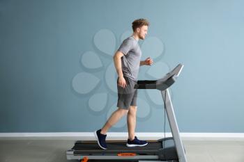 Sporty young man training on treadmill in gym�