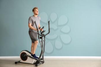 Sporty young man training on machine in gym�