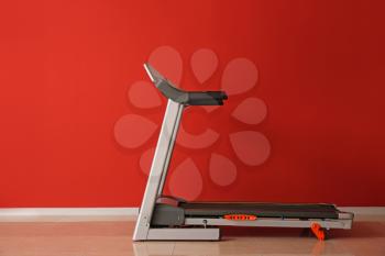 Modern treadmill near color wall�