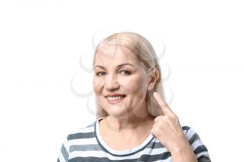 Mature woman with hearing aid on white background�