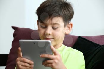 Little boy with hearing aid using tablet computer at home�