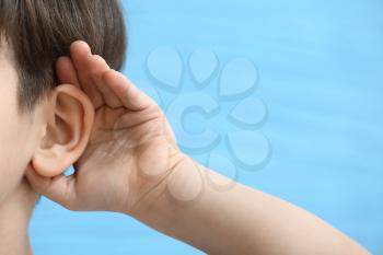 Little boy with hearing problem on color background, closeup�