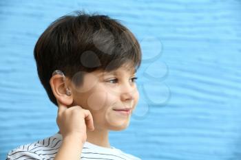 Little boy with hearing aid on color background�
