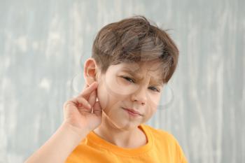 Little boy with hearing problem on grey background�