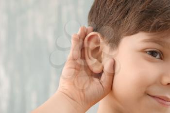 Little boy with hearing problem on grey background, closeup�
