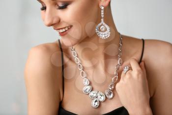 Young woman with beautiful jewelry on light background, closeup�