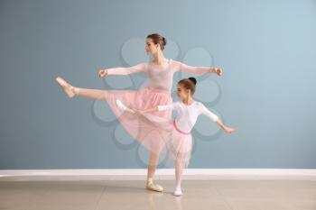 Little ballerina with coach against color wall�