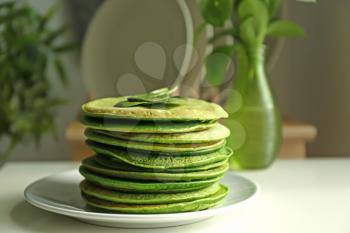 Plate with tasty green pancakes on table in kitchen�
