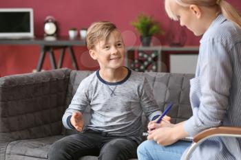 Female psychologist working with little boy in office�