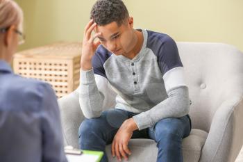 Female psychologist working with depressed teenage boy in office�