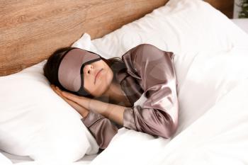 Young woman with sleep mask in bed�