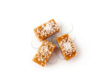 Tasty salty caramel candies on white background�