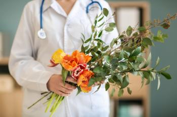 Female doctor with bouquet of beautiful flowers in clinic�