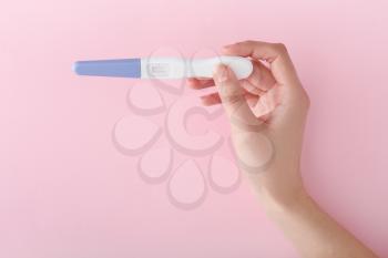 Female hand with pregnancy test on color background�
