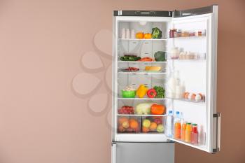 Open fridge full of food near color wall�