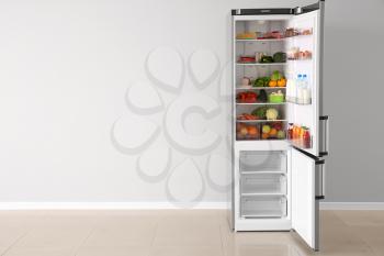 Open fridge full of food near white wall�