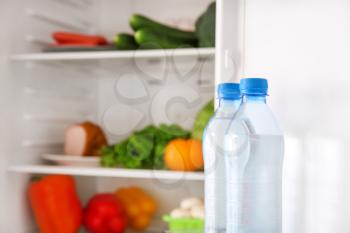 Bottles of water in open fridge�