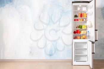 Open fridge full of food near color wall�
