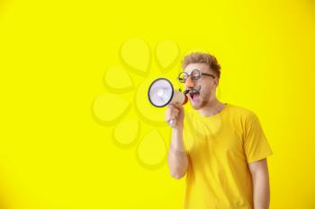 Funny man with megaphone on color background. April Fools' Day prank�
