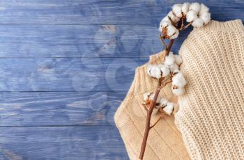 Cotton flowers with knitted sweaters on wooden background�