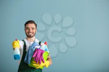 Portrait of male janitor with cleaning supplies on grey background�