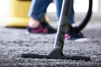 Woman cleaning carpet with hoover at home�