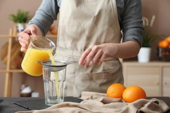 Woman preparing orange juice in kitchen�