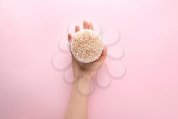Female hand with massage brush on color background�