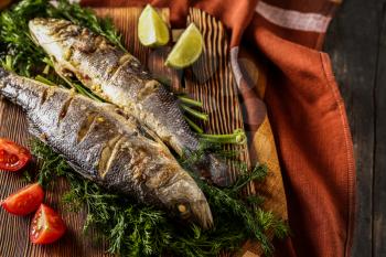 Tasty cooked fish on wooden board�