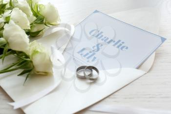 Wedding invitation, rings and flowers on table�