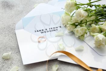 Wedding invitation, ring and flowers on table�